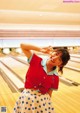 A woman in a red shirt and polka dot skirt posing for a picture.