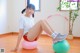 A woman sitting on an exercise ball in a room.