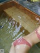 A woman in a pink bikini laying in a pool of water.