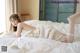 a woman laying on top of a bed in a white dress