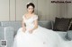 A woman in a wedding dress sitting on a couch.