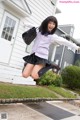 A young woman in a school uniform jumping in the air.