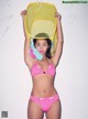 A woman in a pink bikini holding a yellow net over her head.