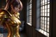 A woman in a gold outfit standing in front of a window.